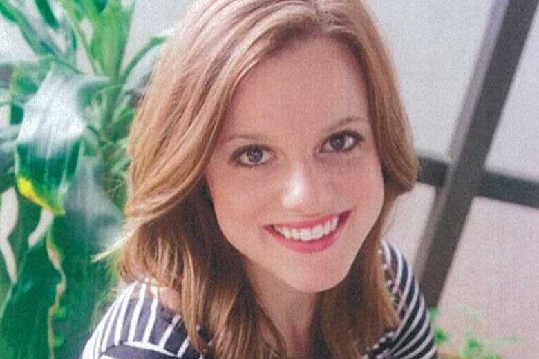 smiling young woman with large eyes in front of a plant