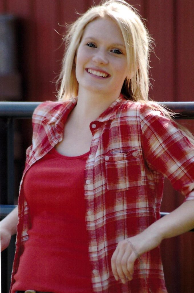 smiling young woman in red flannels leaning on metal railing