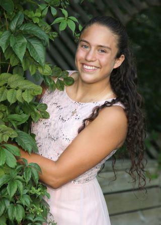 smiling young woman peeking from behind foliage