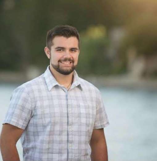 smiling young man posing in front of water