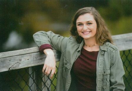 smiling young woman leaning up against wooden railing