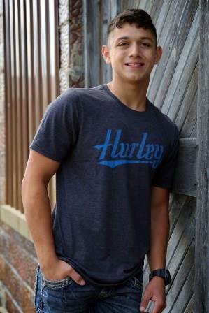 smiling young man leaning up against wooden fence