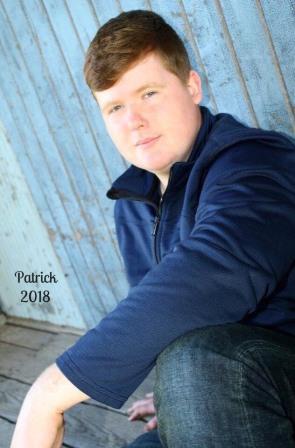 young man leaning up against wooden building