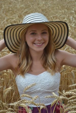 smiling young woman with cute hat posing in wheat field