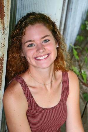 smiling young woman leaning up against a building